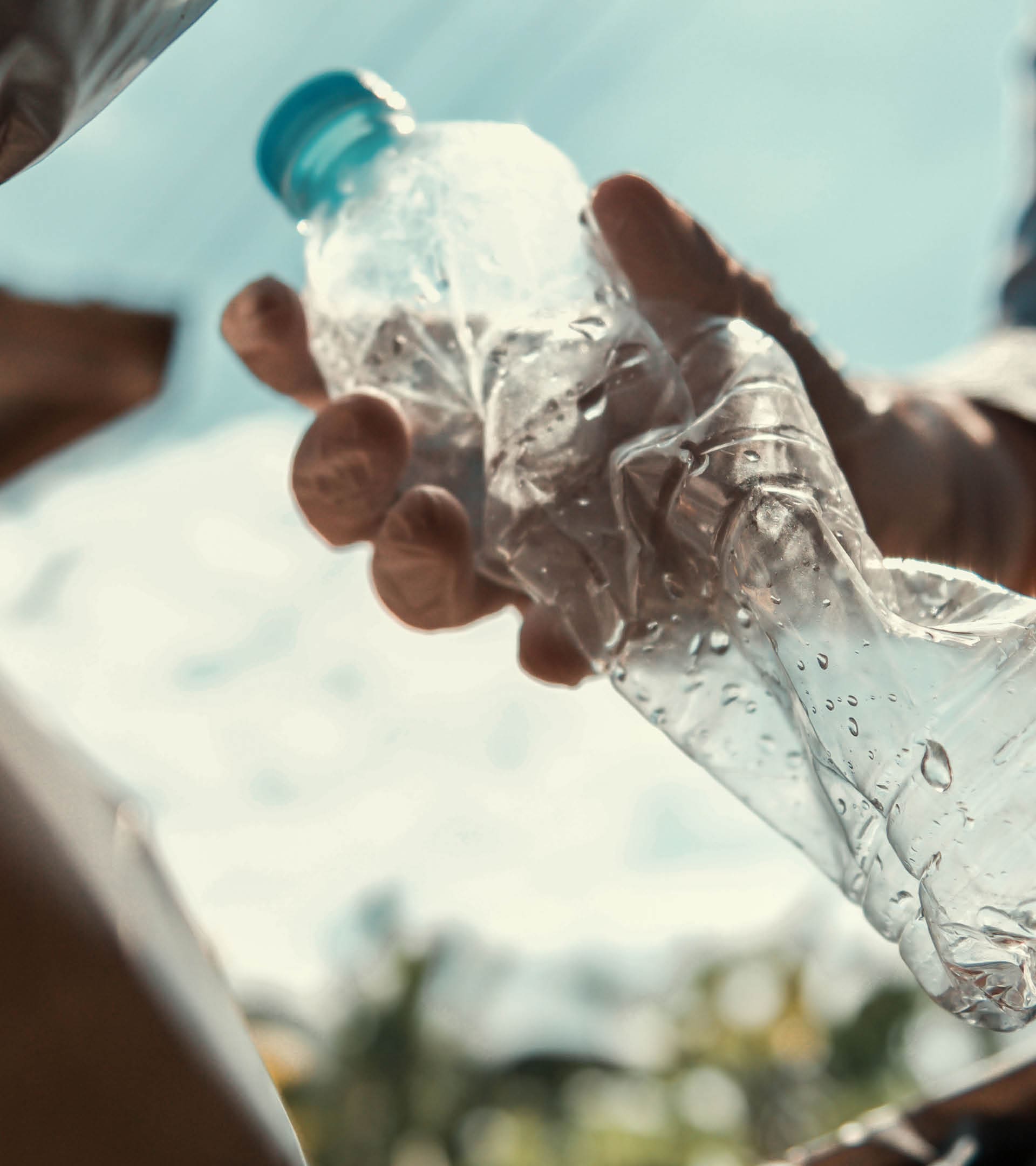 hand putting empty plastic bottle in to garbage black bag